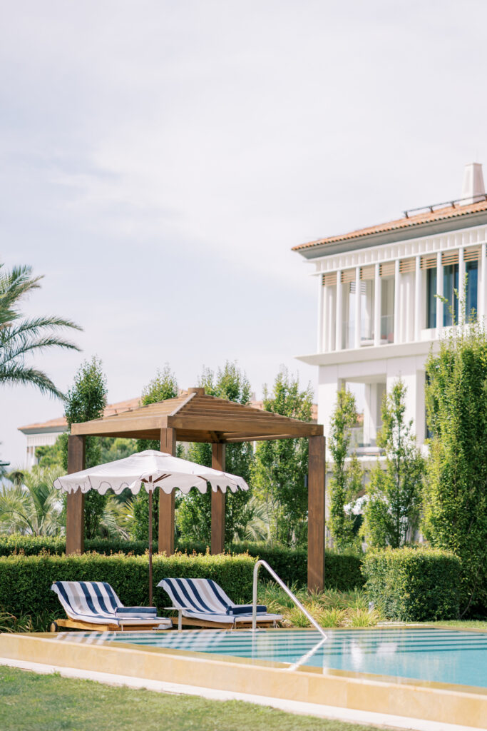 Sun loungers under a sun umbrella by the pool.